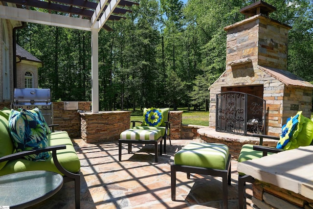 view of patio featuring an outdoor stone fireplace, a pergola, and area for grilling