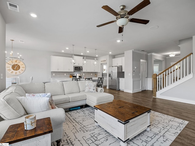 living room featuring ceiling fan with notable chandelier and hardwood / wood-style flooring