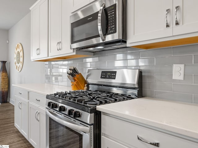 kitchen with light stone countertops, dark hardwood / wood-style flooring, decorative backsplash, white cabinets, and appliances with stainless steel finishes