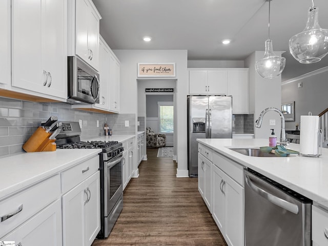 kitchen featuring white cabinetry, sink, hanging light fixtures, and appliances with stainless steel finishes