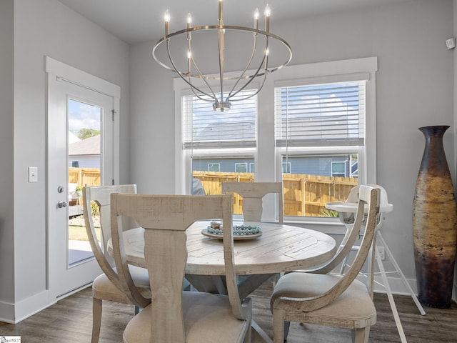 dining area featuring dark wood-type flooring, a healthy amount of sunlight, and a notable chandelier