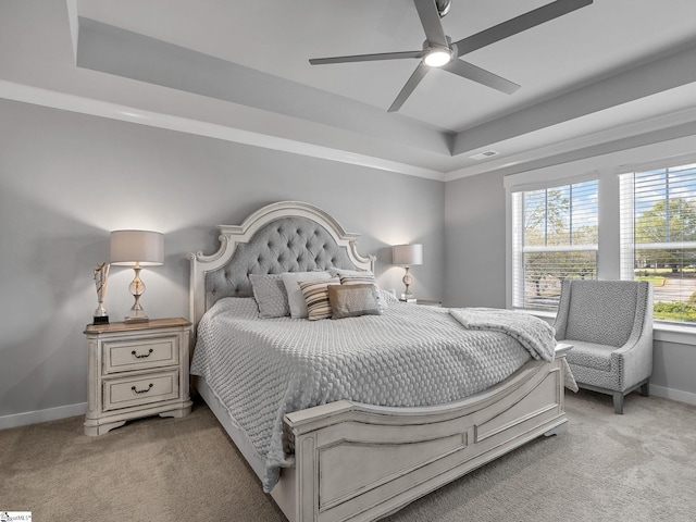 carpeted bedroom with a tray ceiling, multiple windows, and ceiling fan