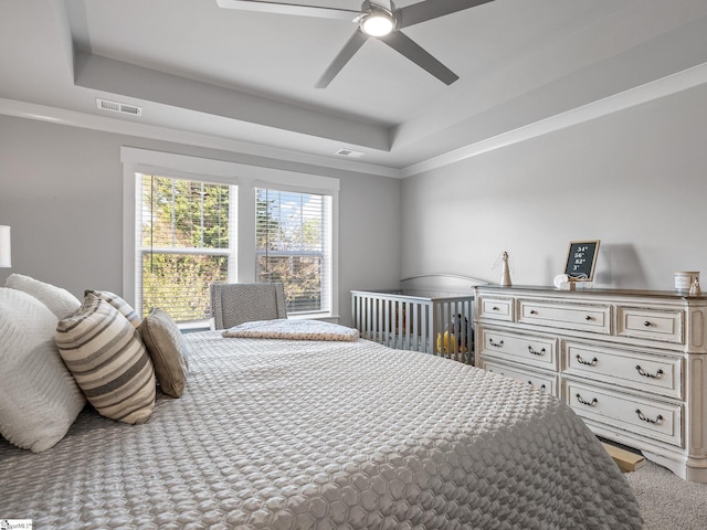 bedroom featuring ceiling fan, a raised ceiling, and ornamental molding