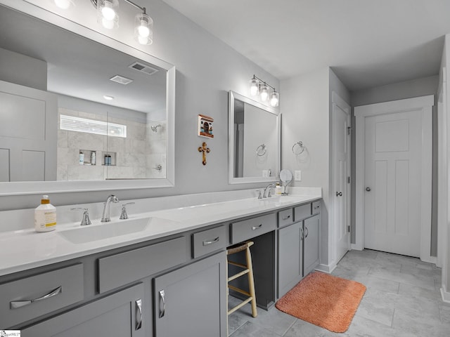 bathroom with tile patterned flooring, vanity, and a tile shower