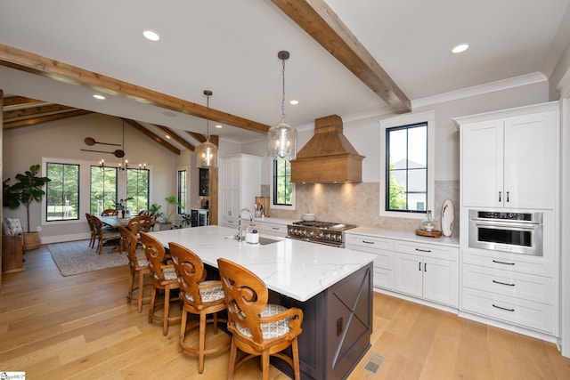 kitchen with custom exhaust hood, white cabinetry, a kitchen island with sink, and appliances with stainless steel finishes