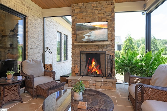 sunroom featuring wood ceiling and an outdoor stone fireplace