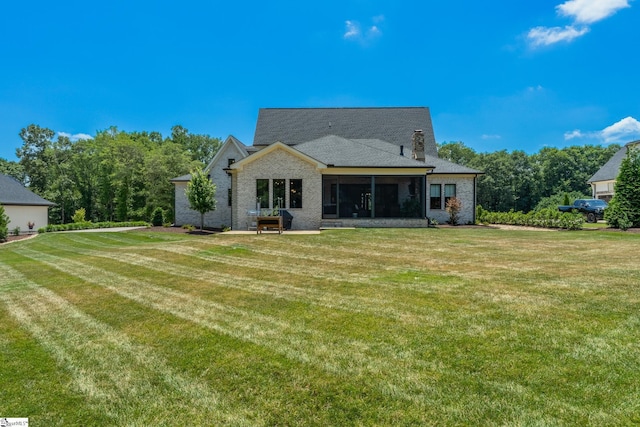 back of house with a lawn and a sunroom