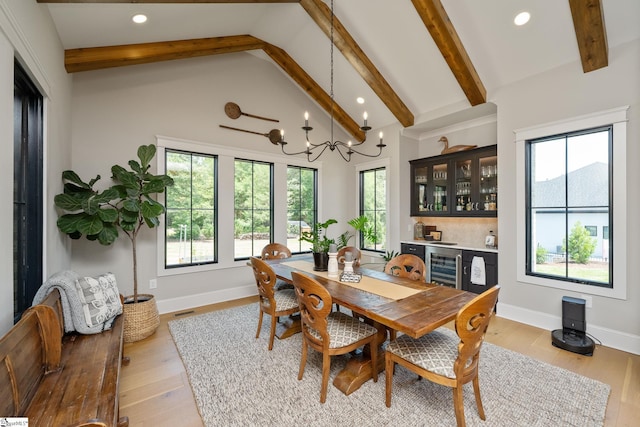 dining room featuring beamed ceiling, an inviting chandelier, beverage cooler, and light hardwood / wood-style flooring