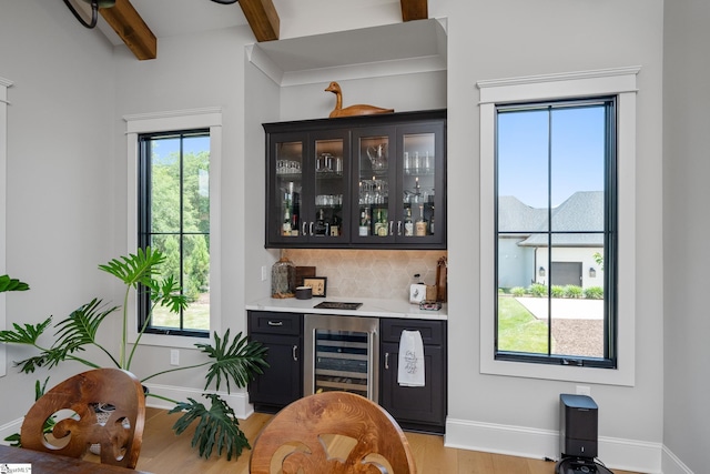 bar with beam ceiling, light wood-type flooring, tasteful backsplash, and wine cooler