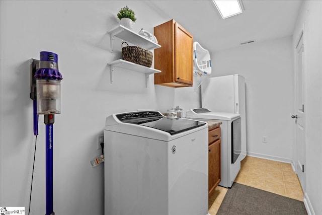 laundry area featuring cabinets, light tile patterned floors, and washing machine and clothes dryer