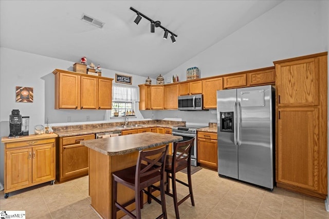 kitchen featuring a breakfast bar, a center island, rail lighting, sink, and stainless steel appliances