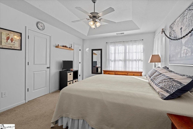 carpeted bedroom featuring a raised ceiling and ceiling fan