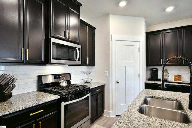 kitchen with backsplash, light wood-type flooring, sink, and appliances with stainless steel finishes