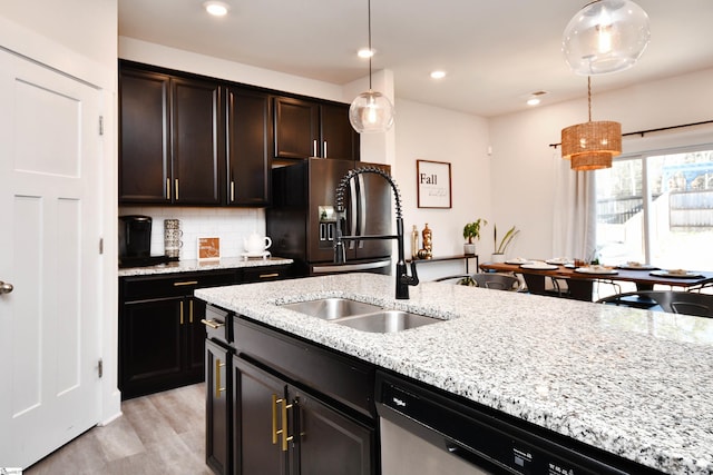 kitchen featuring appliances with stainless steel finishes, tasteful backsplash, sink, light hardwood / wood-style floors, and hanging light fixtures