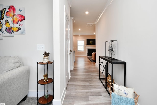 hall with crown molding and light wood-type flooring