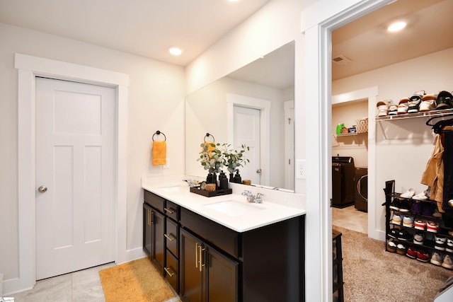 bathroom featuring tile patterned flooring, vanity, and washer / dryer