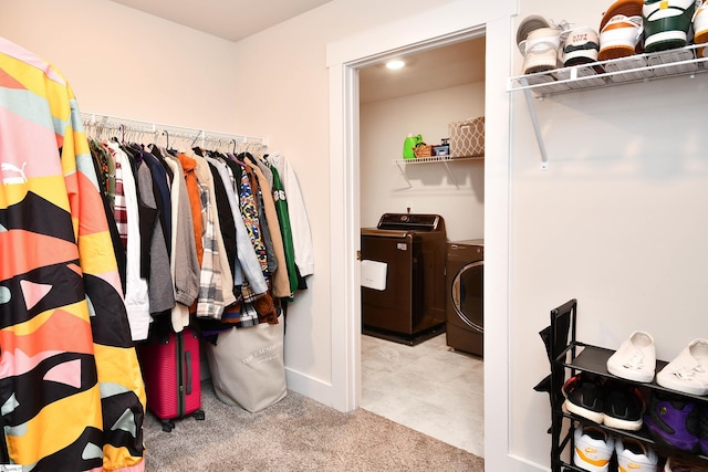 walk in closet featuring washing machine and clothes dryer and light colored carpet