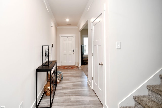 corridor with light wood-type flooring and crown molding