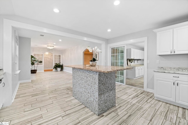 kitchen with light stone counters, a breakfast bar, and white cabinets