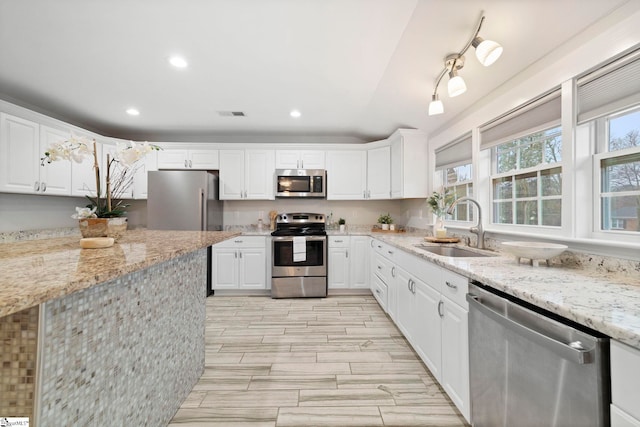 kitchen with light stone counters, sink, white cabinetry, and stainless steel appliances