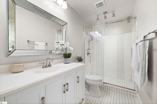 bathroom featuring tile patterned floors, vanity, toilet, and a shower with shower door