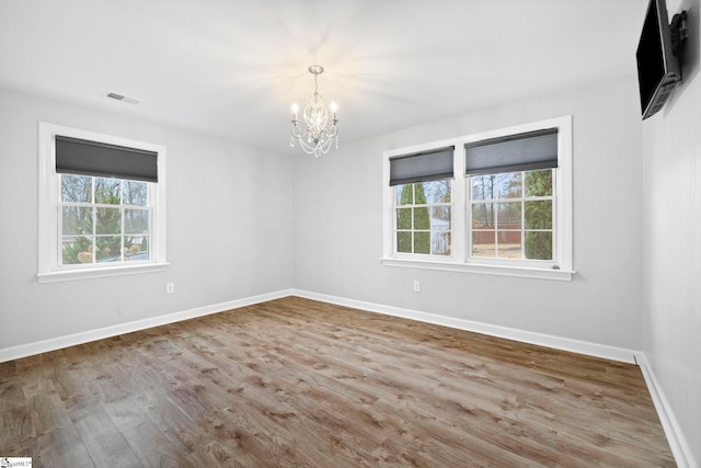 unfurnished room with hardwood / wood-style flooring and an inviting chandelier