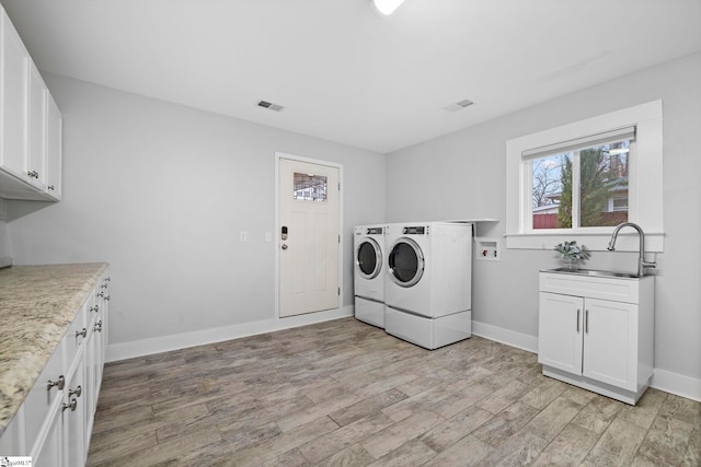 washroom featuring cabinets, separate washer and dryer, sink, and light hardwood / wood-style flooring