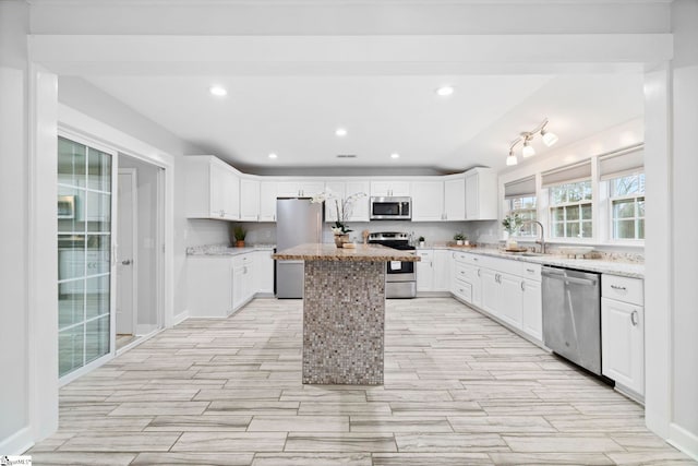 kitchen with a kitchen island, sink, white cabinetry, and stainless steel appliances