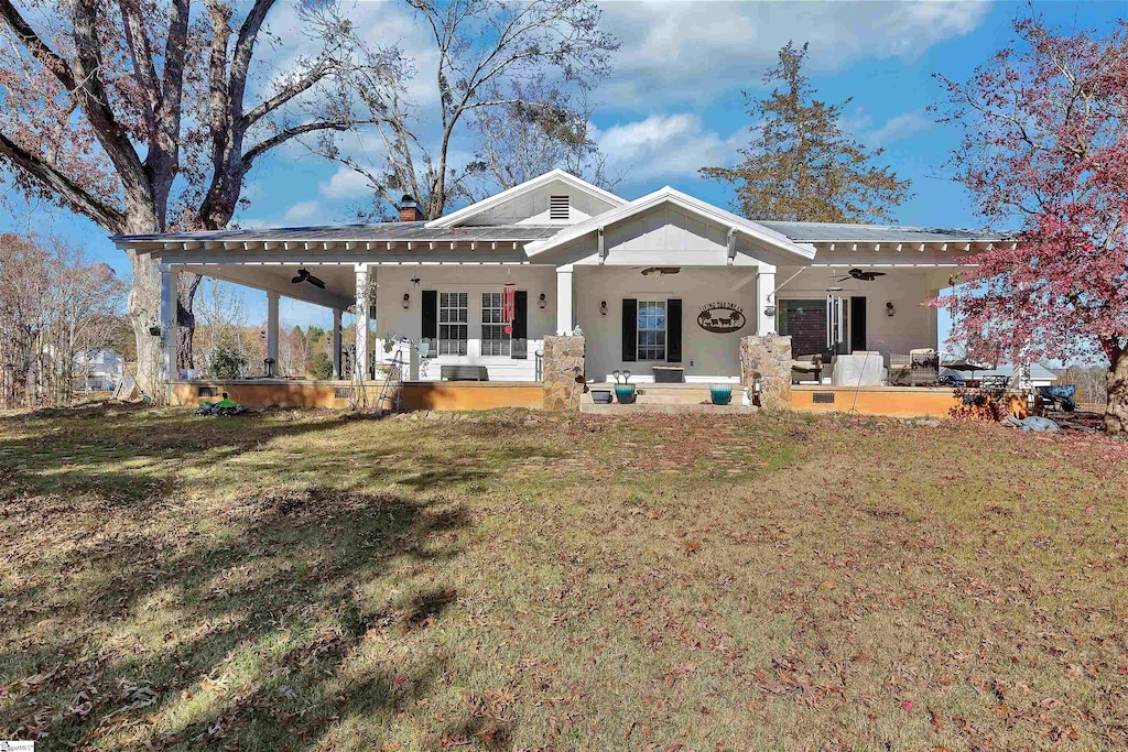 rear view of house with covered porch, ceiling fan, and a lawn