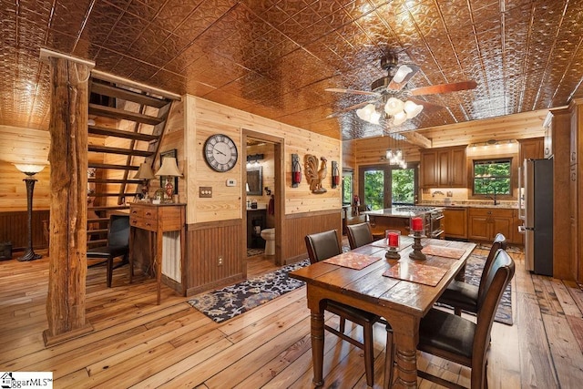 dining area with light hardwood / wood-style flooring, ceiling fan, and wooden walls