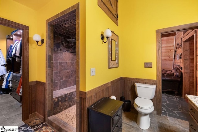 bathroom with a tile shower, vanity, and toilet