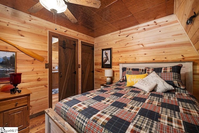 bedroom featuring ceiling fan and wooden walls