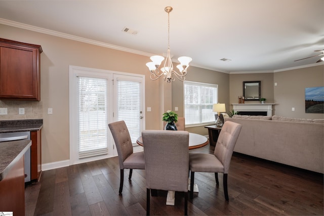 dining area featuring ceiling fan with notable chandelier, crown molding, and dark wood-type flooring