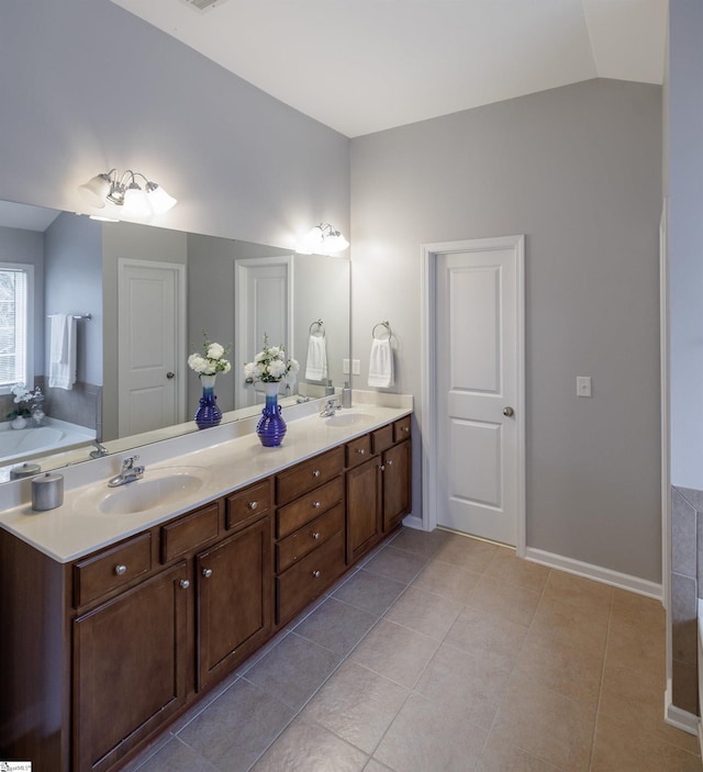 bathroom with vanity, a tub to relax in, tile patterned floors, and lofted ceiling