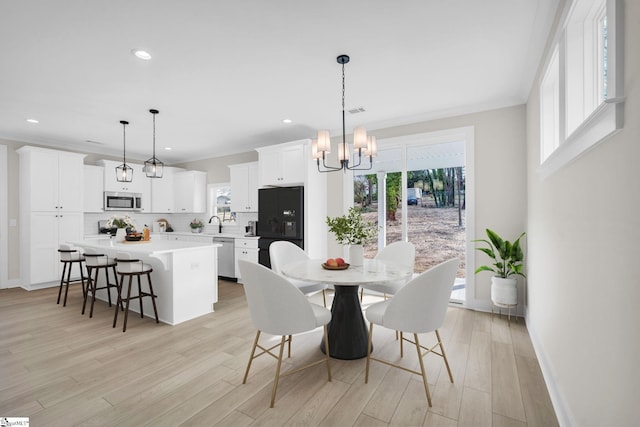 dining area featuring plenty of natural light, an inviting chandelier, and light hardwood / wood-style flooring