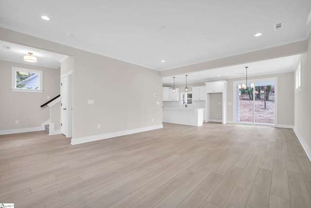 unfurnished living room featuring light hardwood / wood-style floors, an inviting chandelier, and a wealth of natural light