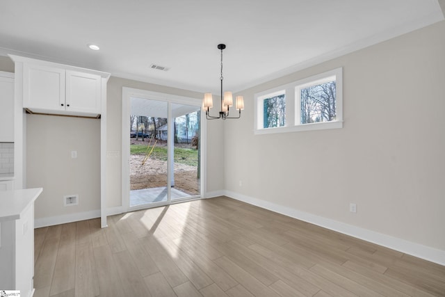 unfurnished dining area featuring light hardwood / wood-style flooring, an inviting chandelier, plenty of natural light, and crown molding