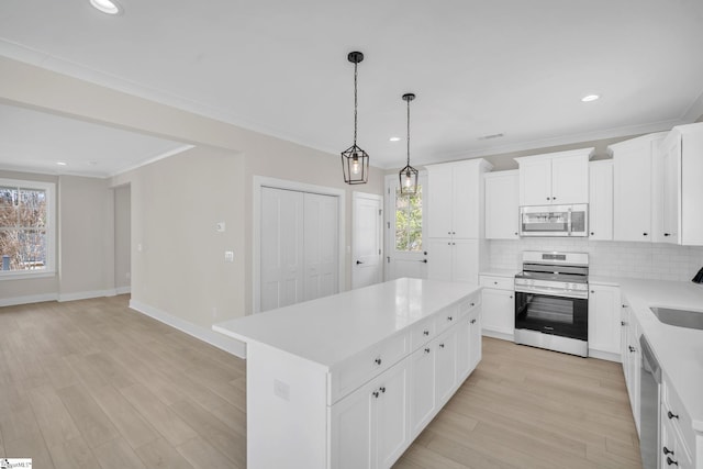 kitchen featuring white cabinets, appliances with stainless steel finishes, a center island, and a healthy amount of sunlight