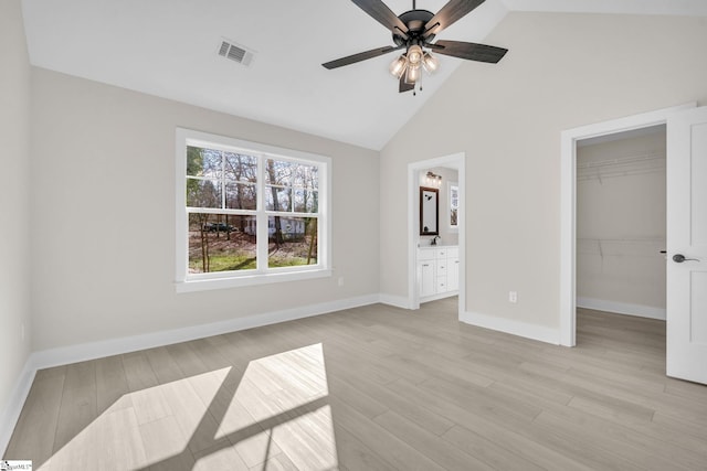 unfurnished bedroom with a walk in closet, light hardwood / wood-style flooring, ensuite bath, ceiling fan, and a closet