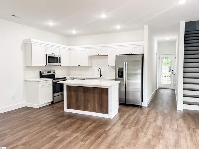 kitchen with white cabinets, appliances with stainless steel finishes, a kitchen island, and sink