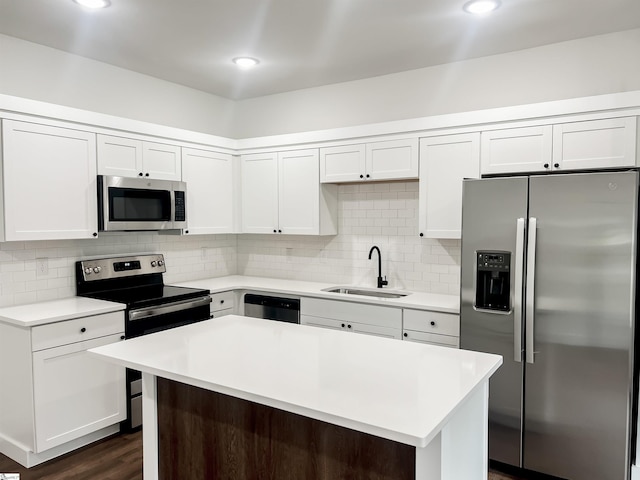 kitchen with white cabinets, appliances with stainless steel finishes, a center island, and sink