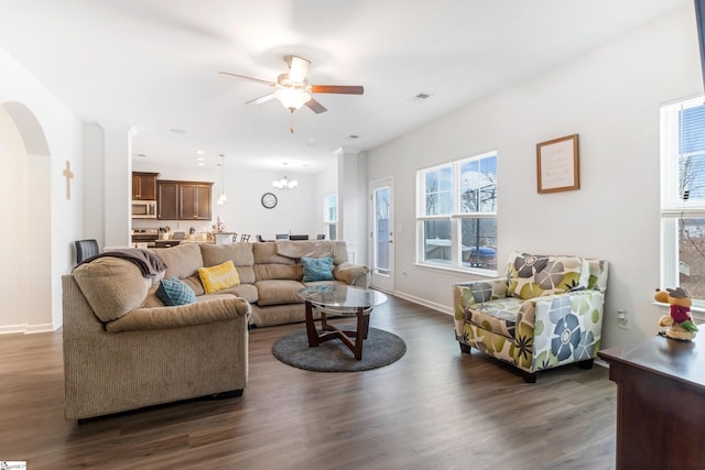 living room with dark wood-type flooring and ceiling fan with notable chandelier