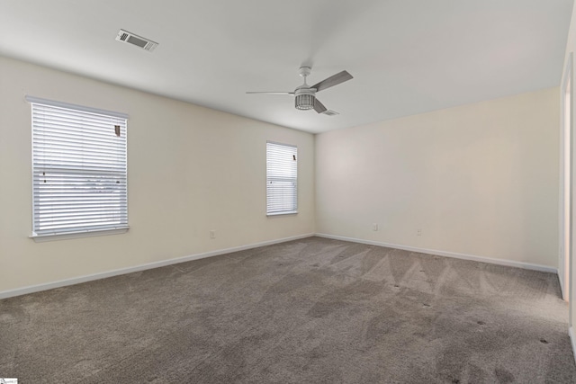 carpeted spare room with ceiling fan and plenty of natural light