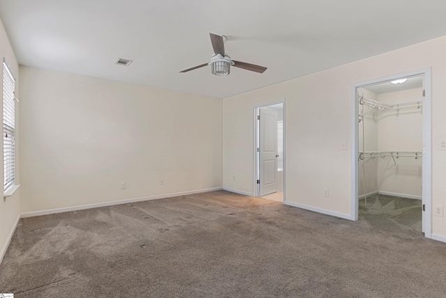 unfurnished bedroom featuring a closet, a spacious closet, ceiling fan, and light colored carpet