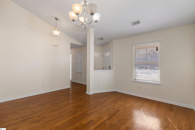 spare room with a chandelier, dark wood-type flooring, and vaulted ceiling