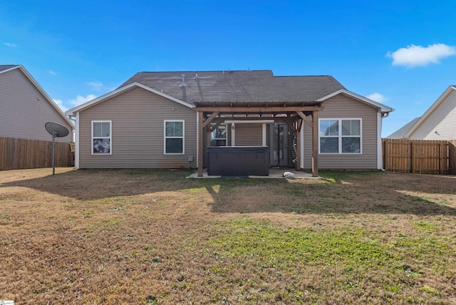 back of property featuring a yard, a pergola, and a hot tub