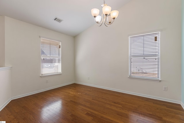 spare room featuring dark hardwood / wood-style flooring, vaulted ceiling, and a notable chandelier