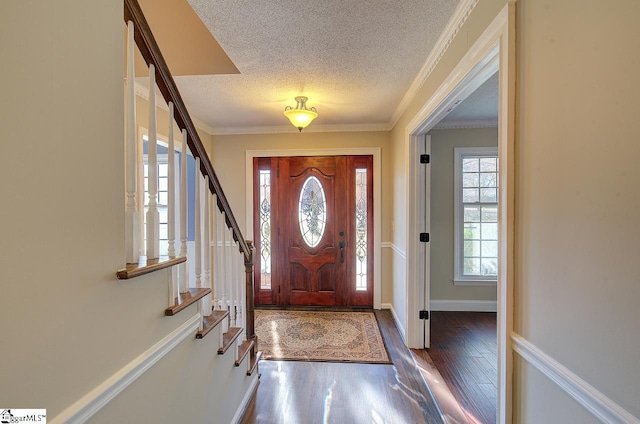 foyer entrance with dark wood-type flooring, a textured ceiling, and ornamental molding