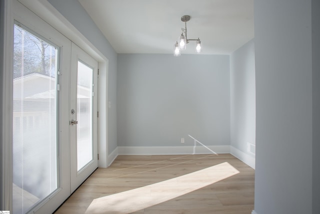 unfurnished dining area featuring a chandelier and french doors