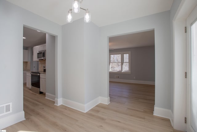 hallway featuring light hardwood / wood-style flooring and a notable chandelier